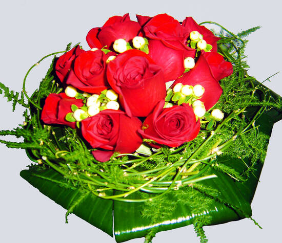 Ramo de novia tipo nido con rosas rojas y hojas de aspidistra.